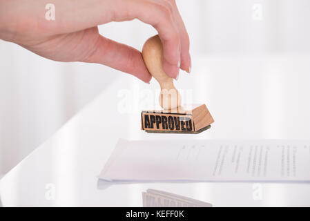 Close-up Of A Person's Hand Stamping Approved On Contract Paper Stock Photo