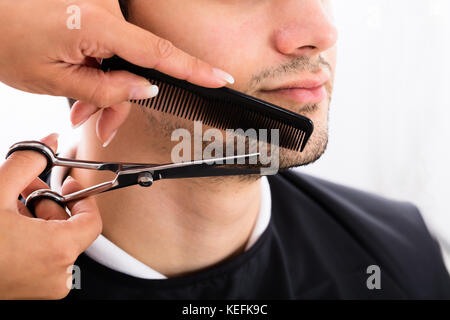 Close-up Of A Hairdresser Shaping Man's Beard With Scissor And Comb At Spa Stock Photo