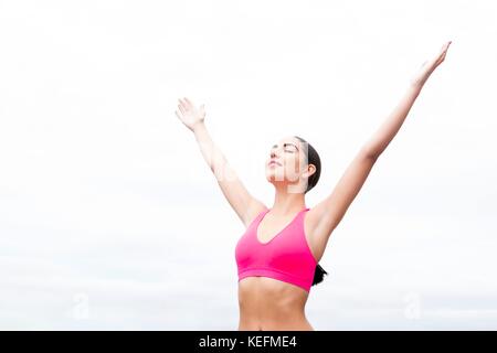 MODEL RELEASED. Young woman wearing sports bra with arms up. Stock Photo