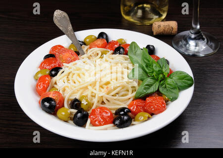 Spaghetti with olives, cherry tomatoes, sprinkled   Parmesan and basil Stock Photo