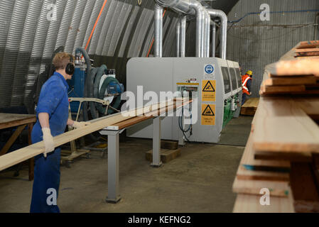 GREYMOUTH, NEW ZEALAND, 18 JULY, 2017: Workers use a four sider machine to plane rough edges from four sides of large pine planks in a Stock Photo