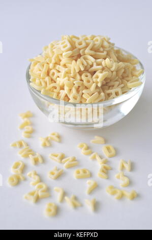 Alphabet pasta for children's meals. ABC pasta. Dry pasta in a glass bowl isolated on white, close up.