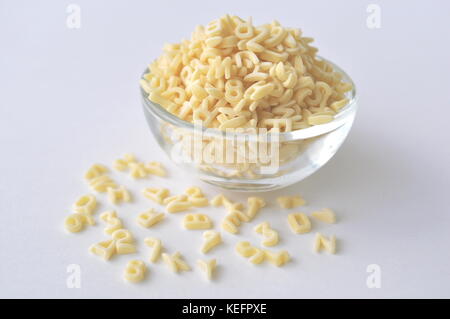Alphabet pasta for children's meals. ABC pasta. Dry pasta in a glass bowl isolated on white, close up.
