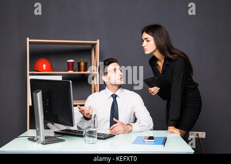 Attractive photo editor pointing at the screen while working with a colleague Stock Photo
