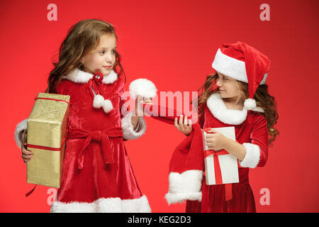 Two happy girls in santa claus hats with gift boxes at studio Stock Photo