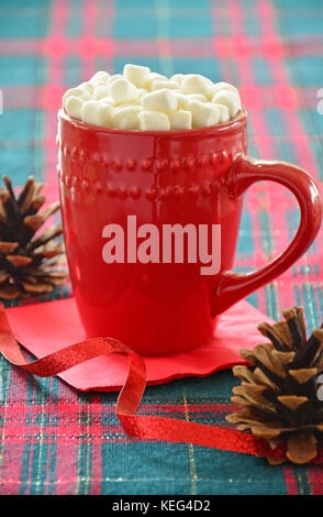 Hot chocolate with marshmallows in festive red mug on tartan background.  Vertical format with selective focus on top of mug. Stock Photo