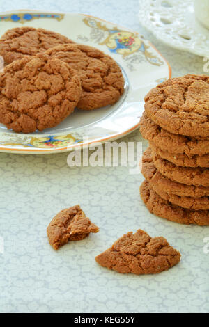 Gingersnaps and tea on old fashioned dishes in vertical format and shot in natural light Stock Photo