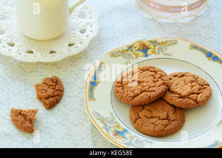 Gingersnaps and tea on old fashioned dishes in horizontal format and shot in natural light Stock Photo