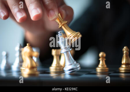 Close up shot hand of business woman moving golden chess to defeat and kill silver king chess on white and black chess board for business challenge co Stock Photo