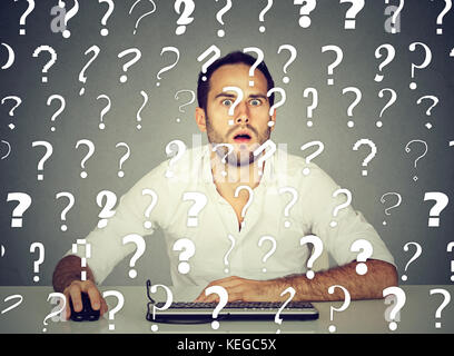 Amazed perplexed man working on desktop computer has many questions Stock Photo