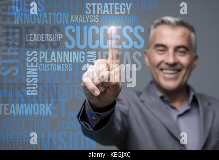 Successful smiling businessman using a virtual touch screen interface and selecting business concepts Stock Photo