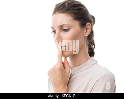 Pensive young woman thinking and touching her lips, white background Stock Photo