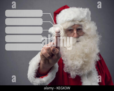 Santa Claus using an interactive touch screen user interface, technology and virtual reality concept Stock Photo