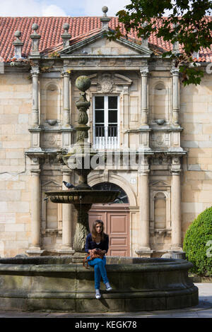 Spanish girl by fountain at Colexio de San Clemente de Pasantes in Santiago de Compostela, Galicia, Spain Stock Photo