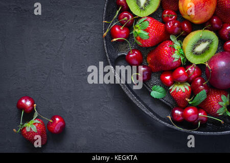 Mix of summer berries and fruits on a black plate. Top view with copy space Stock Photo