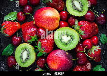 Summer juicy ripe Strawberry, cherry, kiwi and peaches On a black background closeup. Top view Stock Photo