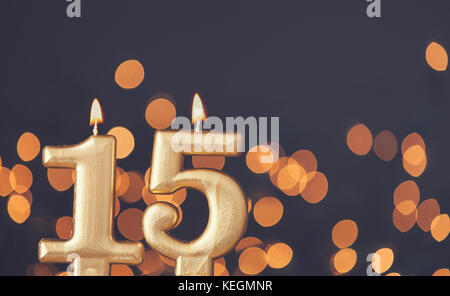 Gold number 15 celebration candle against blurred light background Stock Photo
