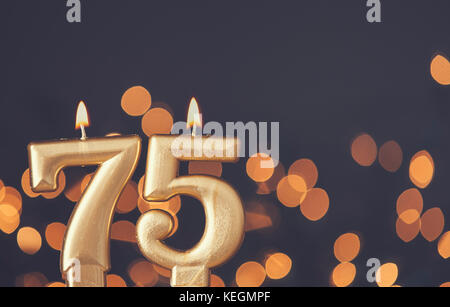 Gold number 75 celebration candle against blurred light background Stock Photo