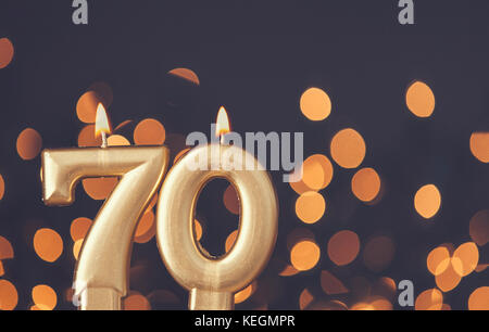 Gold number 70 celebration candle against blurred light background Stock Photo