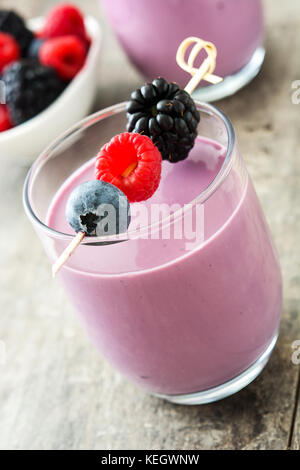 Healthy berry smoothie in glass on wooden table
