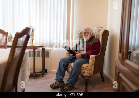 Sad Caucasian man holding picture in chair Stock Photo