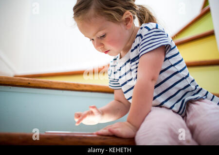Caucasian girl using digital tablet on staircase Stock Photo