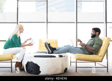 Friends using technology in lounge Stock Photo