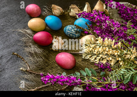 Bouquet of wild flowers and colored Easter eggs on a black background Stock Photo