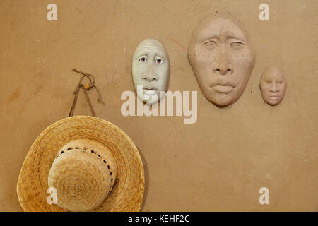 Clay masks and hat hanging on wall Stock Photo