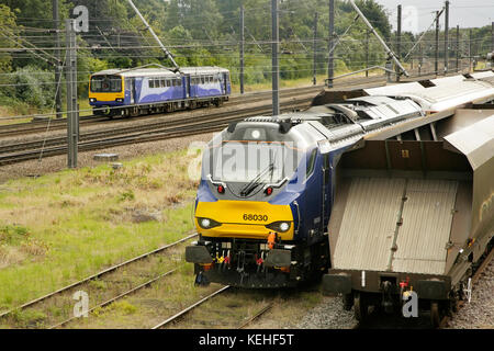 Northern Rail class 144 train passing Direct Rail Services class 68 diesel locomotive 68030 waiting in Holgate sidings south of York station, UK. Stock Photo