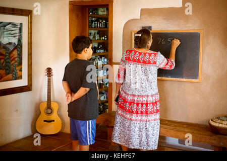 Woman writing equation on blackboard for son Stock Photo