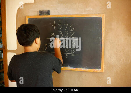 Native American boy solving equation on blackboard Stock Photo