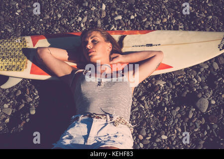 Caucasian woman laying on surfboard on beach Stock Photo