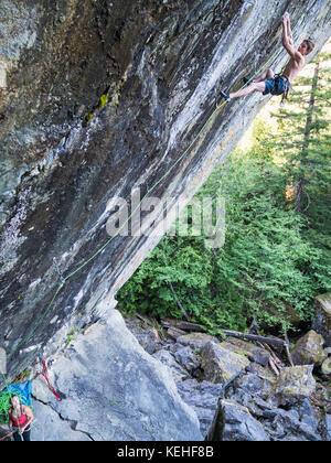Girl watching boy climbing rock Stock Photo