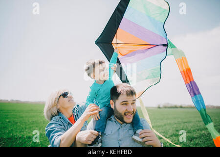 Caucasian boy flying kite with father and grandmother Stock Photo