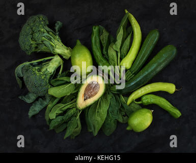 Raw green vegetables set. Broccoli, avocado, pepper, spinach, zuccini and lime on  dark stone background, top view Stock Photo