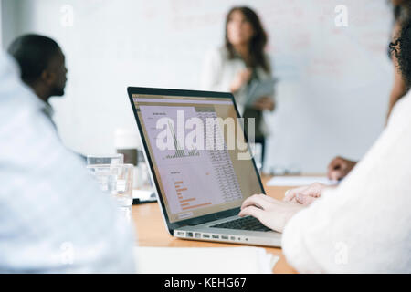 Businesswoman typing on laptop in meeting Stock Photo