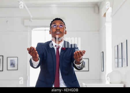 Black man gesturing and looking up in gallery Stock Photo