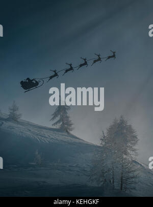 Silhouette of Santa and reindeer flying sleigh in winter Stock Photo