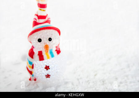 Snowman in striped colorful cap and scarf on the snow background. Christmas decoration Stock Photo