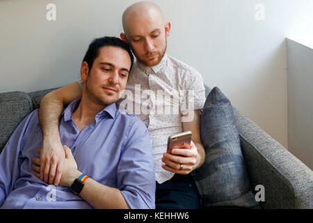 Caucasian men holding hands and texting on cell phone Stock Photo