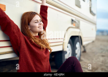 Caucasian woman stretching arms and leaning on motor home Stock Photo