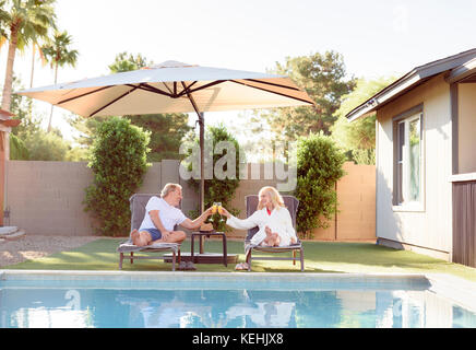 Caucasian couple toasting near swimming pool Stock Photo