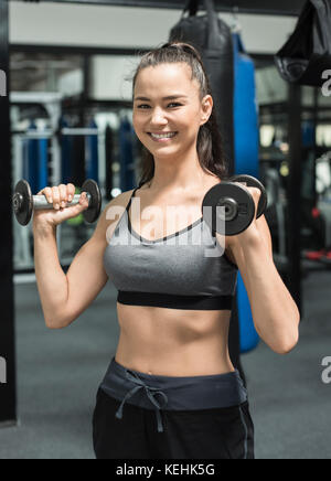 Mixed race woman lifting dumbbells Stock Photo