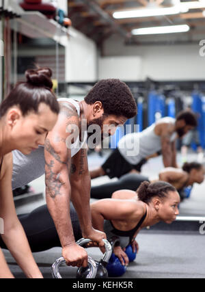 Man and women doing push-ups with kettlebells Stock Photo