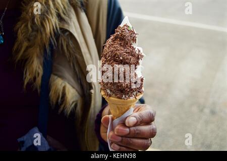 Black lady with ice cream cone at the seaside, Littlehampton, UK Stock Photo