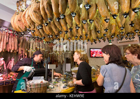 Shoppers in butcher's shop to buy Iberico Jamon Ham and other meats in Calle de Bidebarrieta in Bilbao, Spain Stock Photo