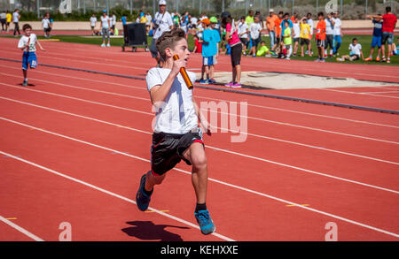 a young boy leading his team for victory in a relay race Stock Photo