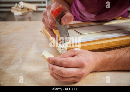 Close-up A male carpenter in work clothes restoring a vintage beige door with wax Stock Photo