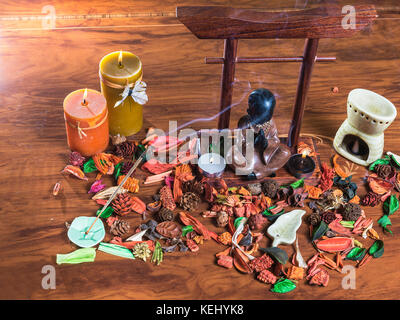 buddha in meditation  on dry flowers with burning candles and incense Stock Photo